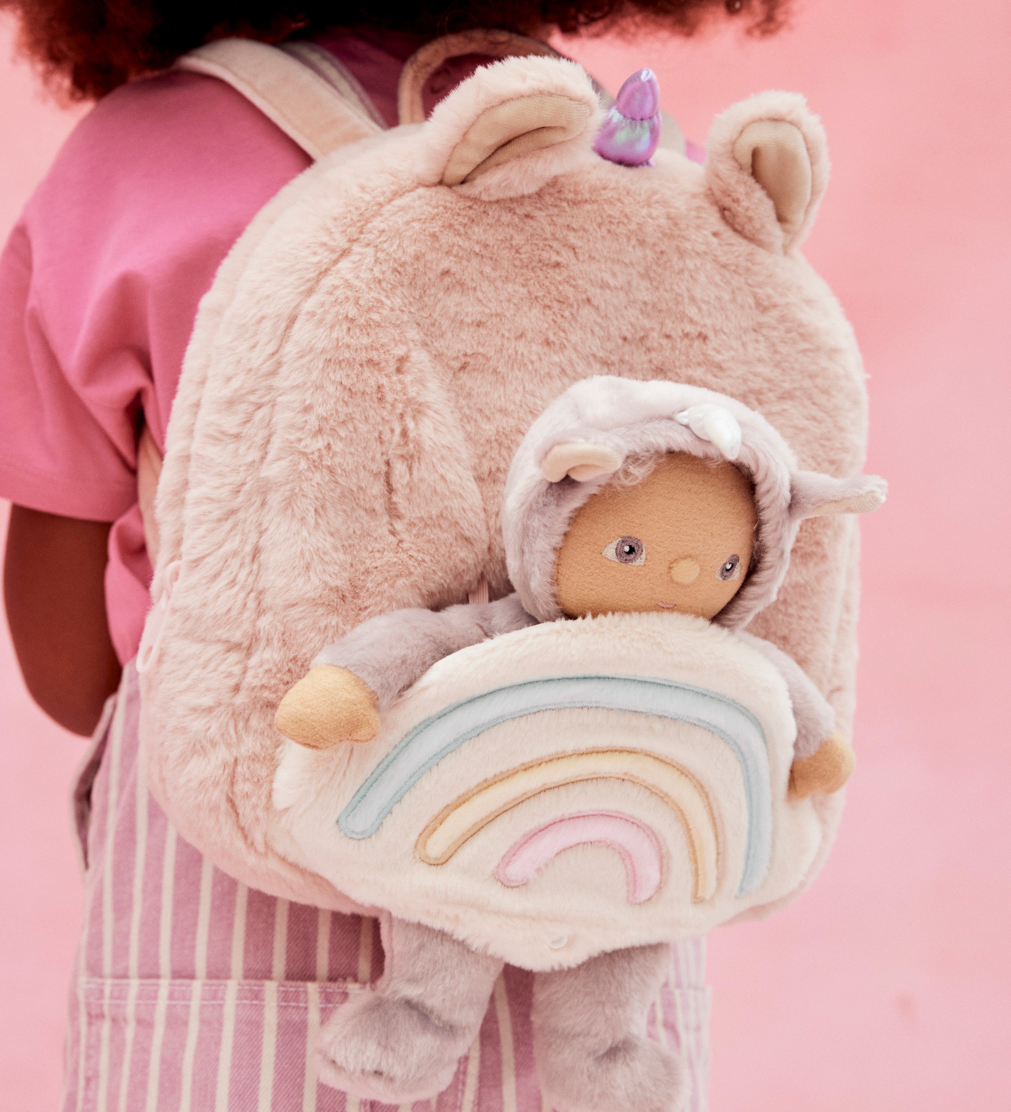 A close up of the pink fluffy backpack with a dinky dinkum doll sitting inside the bag
