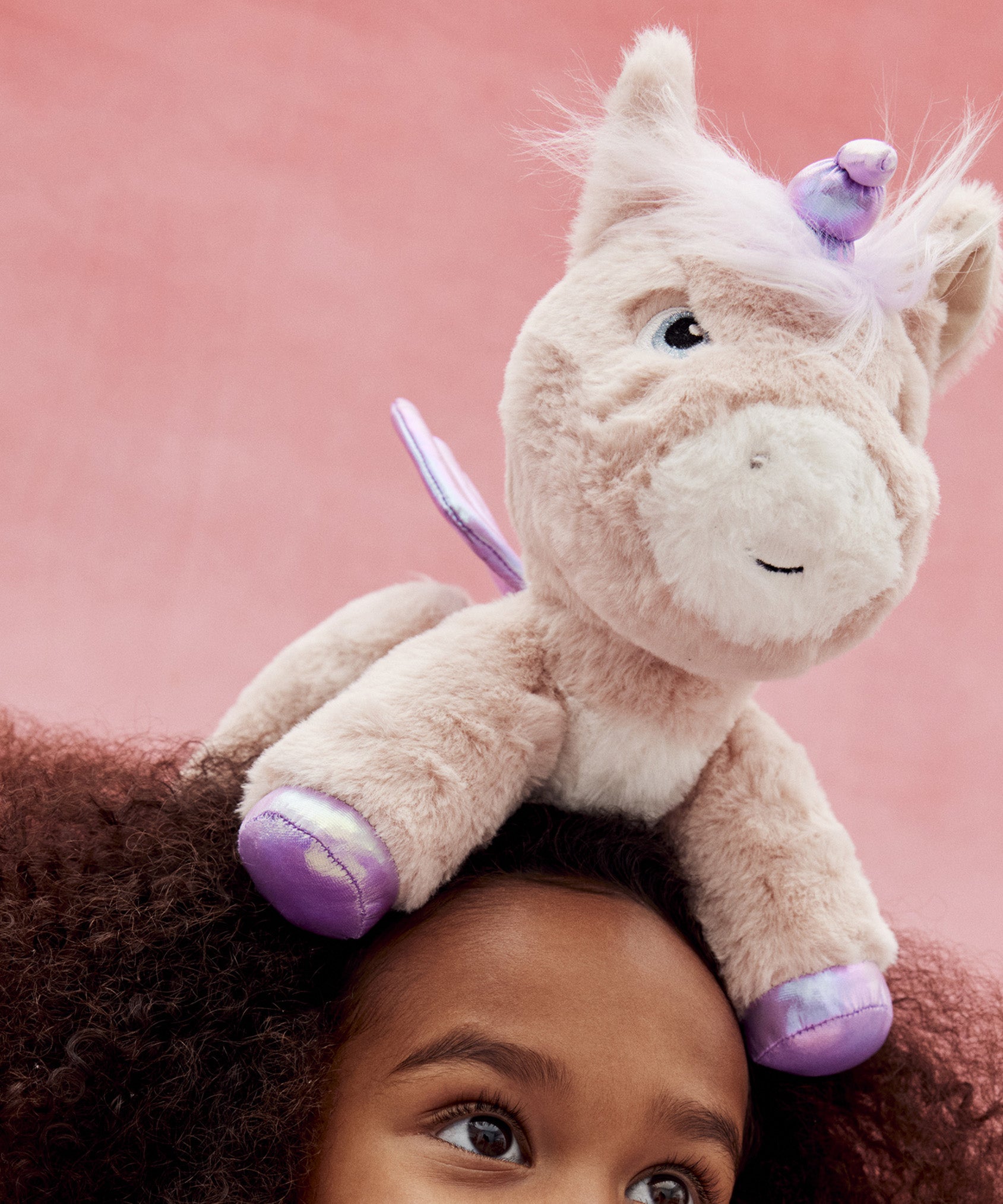 The toy unicorn is balancing on a little girl's head