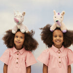 Two children with the Olli Ella Dinkum unicorns balancing on their heads