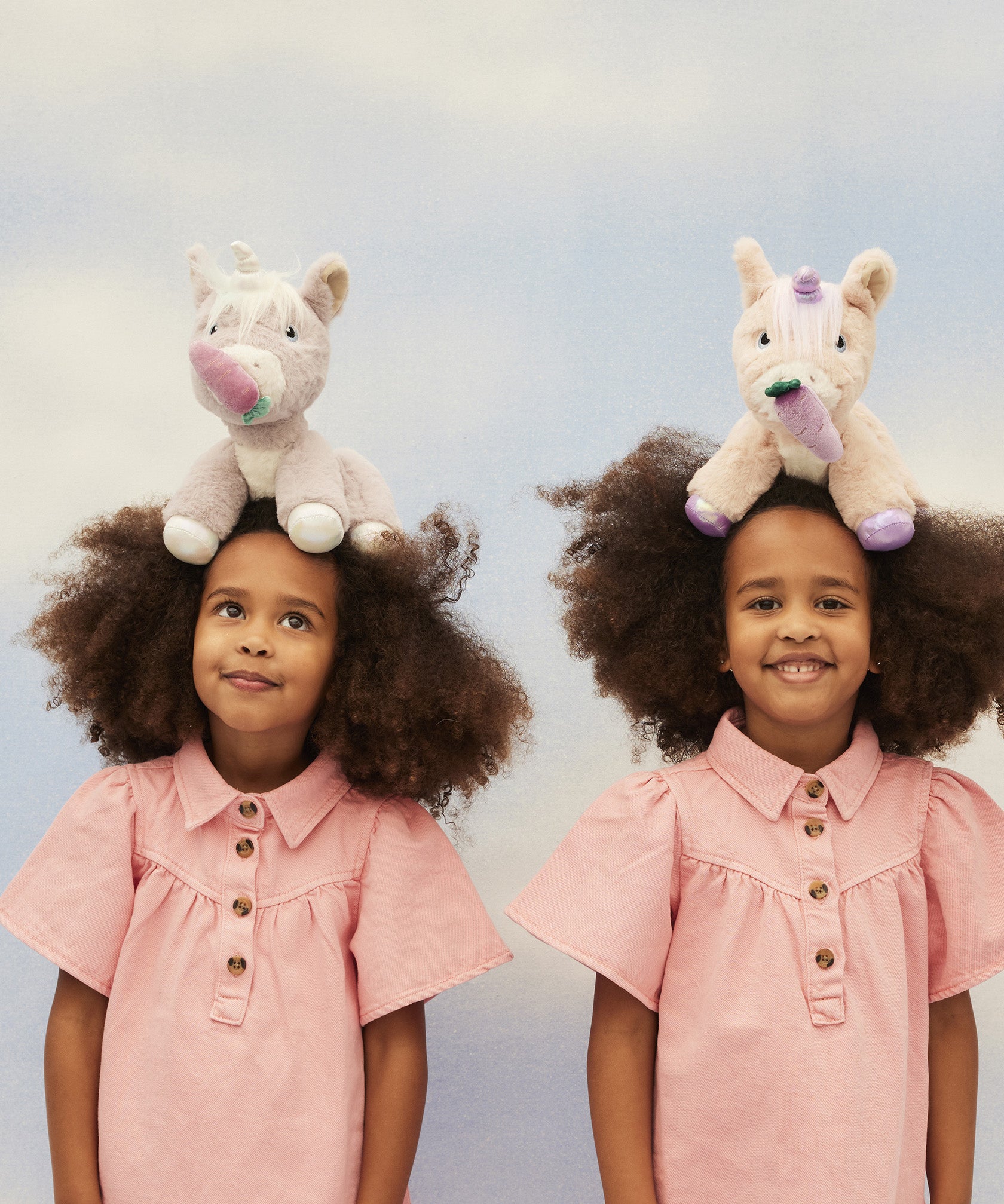 Two children with the Olli Ella Dinkum unicorns balancing on their heads