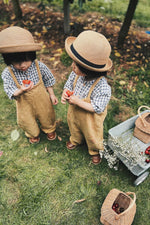 Girl sat down on a blue blanket eating a cake next to the Olli Ella vintage blue wonder wagon