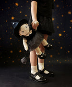 A child carrying the Olli Ella Wendy Witch dream Dinkum doll by their hand. A dinkum doll with a black dress, witches hat, black shoes and a magnetic broom accessory. This doll is part of Olli Ella's Halloween collection available here at Babipur.