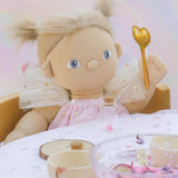 A close up of the Olli Ella Willow dream dinkum doll sitting by a table and showing the doll holding the golden fairy wand