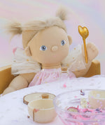 A close up of the Olli Ella Willow dream dinkum doll sitting by a table and showing the doll holding the golden fairy wand