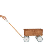 Hand pulling the Olli Ella wooden toy wagon on a white background