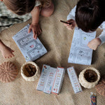 Two children play with the Olli Ella Playpa Children's Colouring Paper Roll Travel Pack  -  Forest Design and Fairytale design in a home setting.