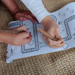 Two children play with the Olli Ella Playpa Children's Colouring Paper Roll Travel Pack  -  Forest Design and Fairytale design in a home setting.