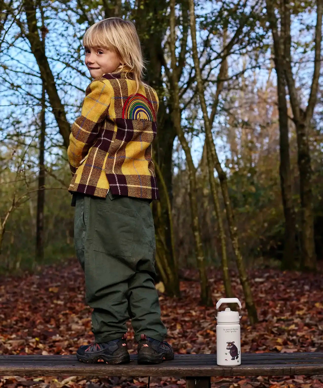 Child standing on a wooden bench next to a stainless steel One Green Bottle in cream with a Gruffalo character design 