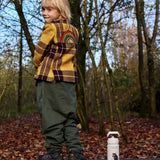 Child standing on a wooden bench next to a stainless steel One Green Bottle in cream with a Gruffalo character design 