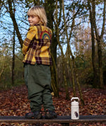 Child standing on a wooden bench next to a stainless steel One Green Bottle in cream with a Gruffalo character design 