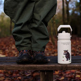 One Green Bottle stainless steel bottle in cream with a Gruffalo design standing on a wooden bench next to child's legs