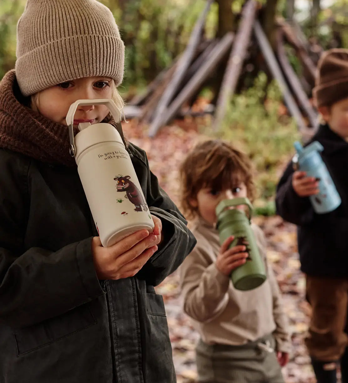 Children standing in a forest and holding a One Green Bottle Stainless steel bottle showing a Gruffalo character