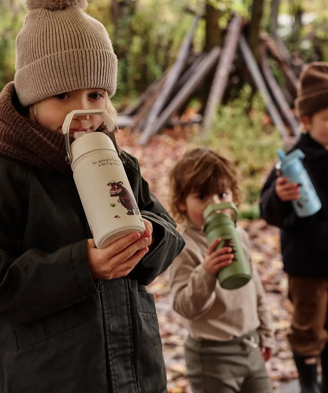 Children standing in a forest and holding a One Green Bottle Stainless steel bottle showing a Gruffalo character