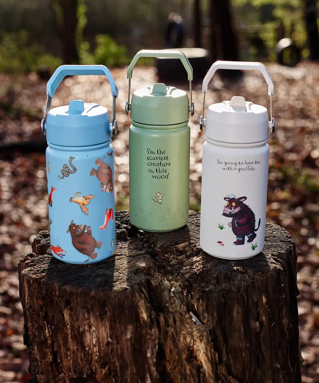 All 3 One Green Bottle collection bottles standing on a tree trunk showing the different Gruffalo characters