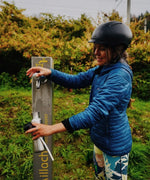 Woman refilling a stainless steel One Green Bottle 800ml water bottle with trees in the background