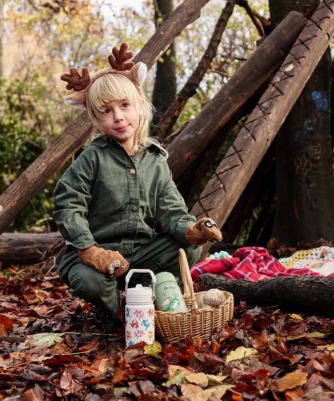 Child sitting next to a cream and green  One Green Bottle Zog collection bottles in the forest 