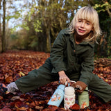 Child standing on autumn leaves and holding the One Green Bottle stainless steel Zog collection bottles
