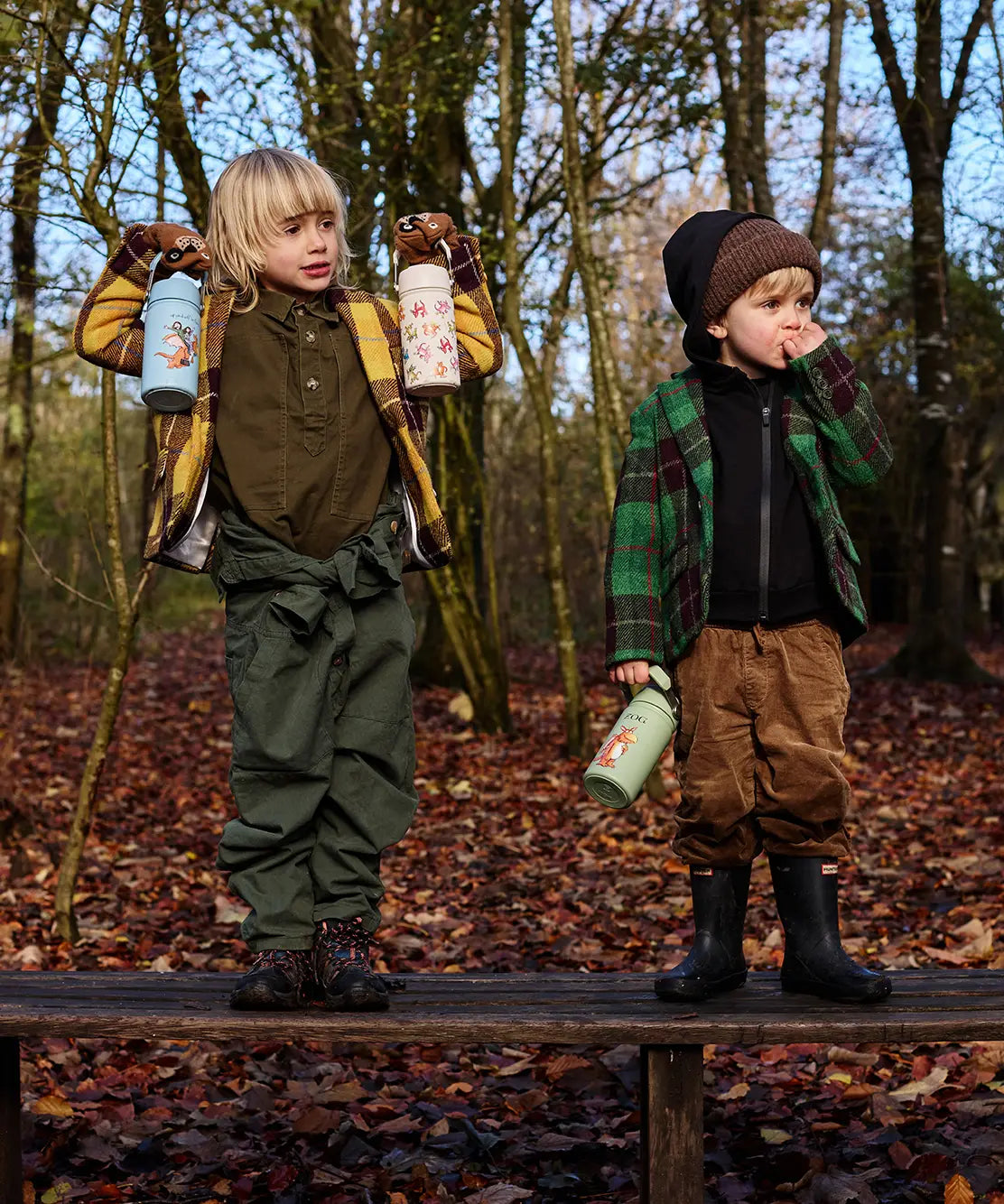 Children standing on a wooden bench and holding the One Green Bottle Zog character collection bottles