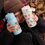 Child holding a blue and cream One Green Bottle stainless steel water bottles showing different Zog characters
