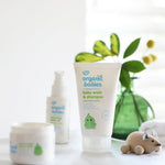 Organic Babies Baby Wash & Shampoo Scent Free placed on a white surface next to a wooden toy mouse. Other products from teh organic babies collection can be seen in the background. 