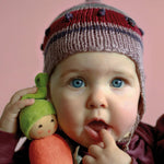 baby holding an organic carrot shaped soft toy which has a face and a green hat