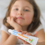 A child holding on a tube of Organic Children Toothpaste Mandarin & Aloe Vera with Fluoride. 