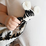 A baby holding the Etta Loves Organic Cotton Baby Comforter - Fern