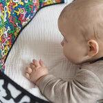 A child look at the 'Baby' print on the Etta Loves X Keith Haring Reversible Baby Sensory Strip
