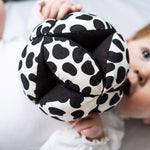 Etta Loves Organic Sensory Grasping Ball with black and white spots, and a black inner, being played with by a child