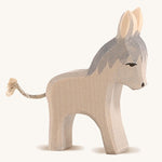 A grey wooden small standing Ostheimer donkey figure on a cream background.