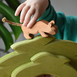 Child placing a small lion on top of the Ostheimer African tree wooden toy figure. 