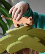 Child placing a small lion on top of the Ostheimer African tree wooden toy figure. 