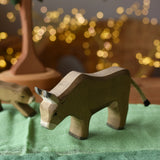 Ostheimer alp cow eating handmade wooden toy figure placed on green cotton play cloths. 