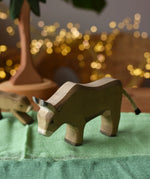 Ostheimer alp cow eating handmade wooden toy figure placed on green cotton play cloths. 