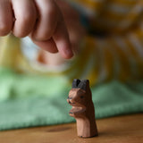 Ostheimer baby kangaroo handmade wooden toy figure placed on a wooden surface with a child's hand reaching for it.
