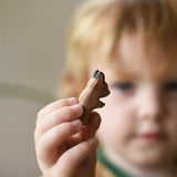 Ostheimer baby kangaroo handmade wooden toy figure in a child's hand being held out in front of the child's face.