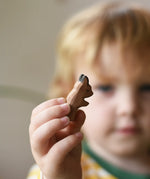Ostheimer baby kangaroo handmade wooden toy figure in a child's hand being held out in front of the child's face.