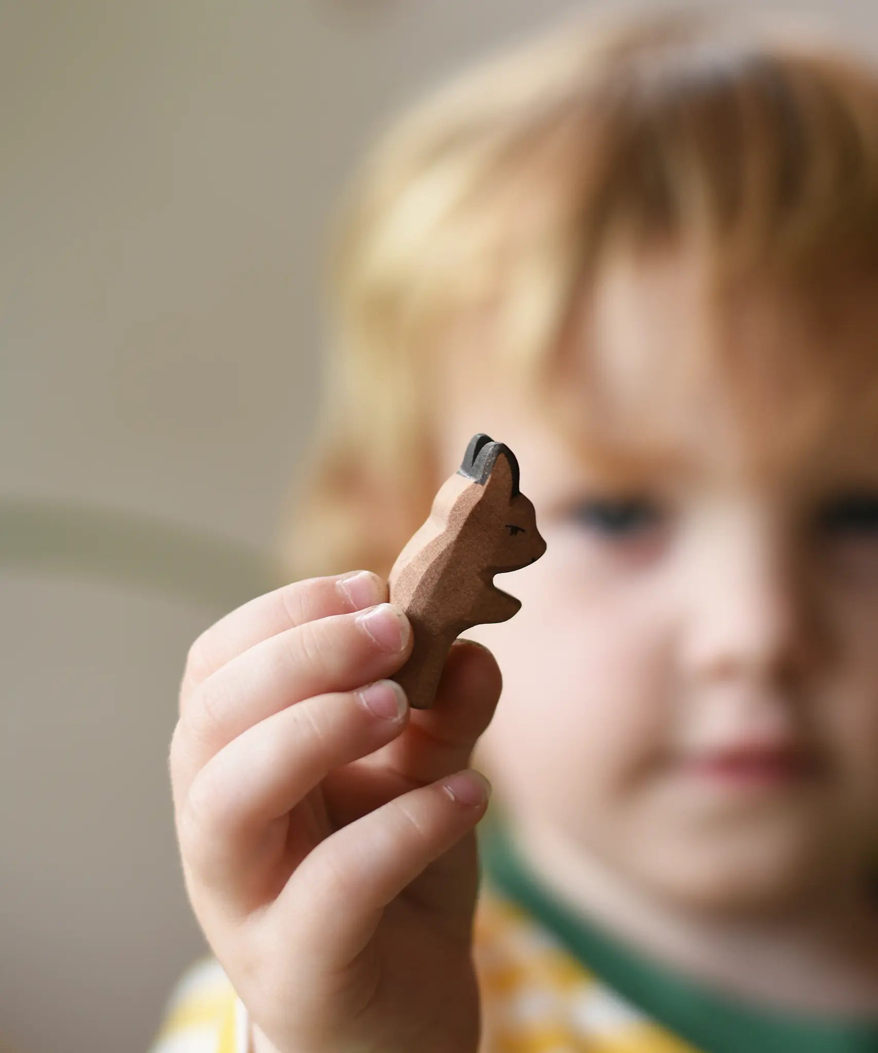 Ostheimer baby kangaroo handmade wooden toy figure in a child's hand being held out in front of the child's face.