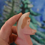A pink coloured Ostheimer little angel held in an adult's hand to show scale. This wooden figure is part of a large range of expertly hand crafted, Waldorf inspired, wooden toys here at Babipur. 