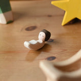 Ostheimer baby wooden toy figure placed on a wooden surface.