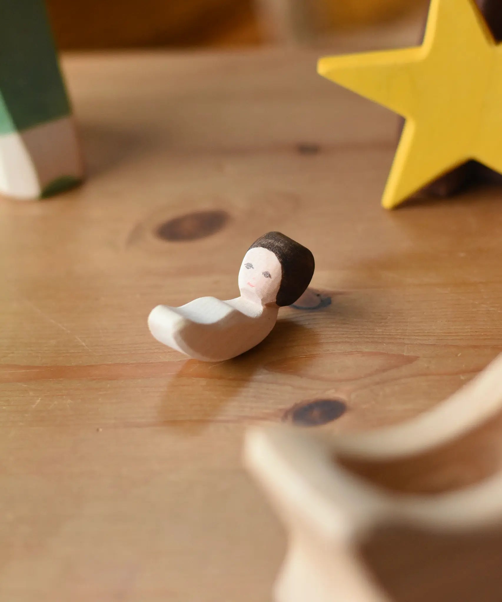 Ostheimer baby wooden toy figure placed on a wooden surface.