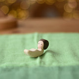 Ostherimer baby wooden toy figure placed on a light green cotton play cloth.