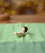Ostherimer baby wooden toy figure placed on a light green cotton play cloth.