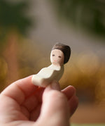 Ostherimer baby wooden toy figure in an adult's hand. 