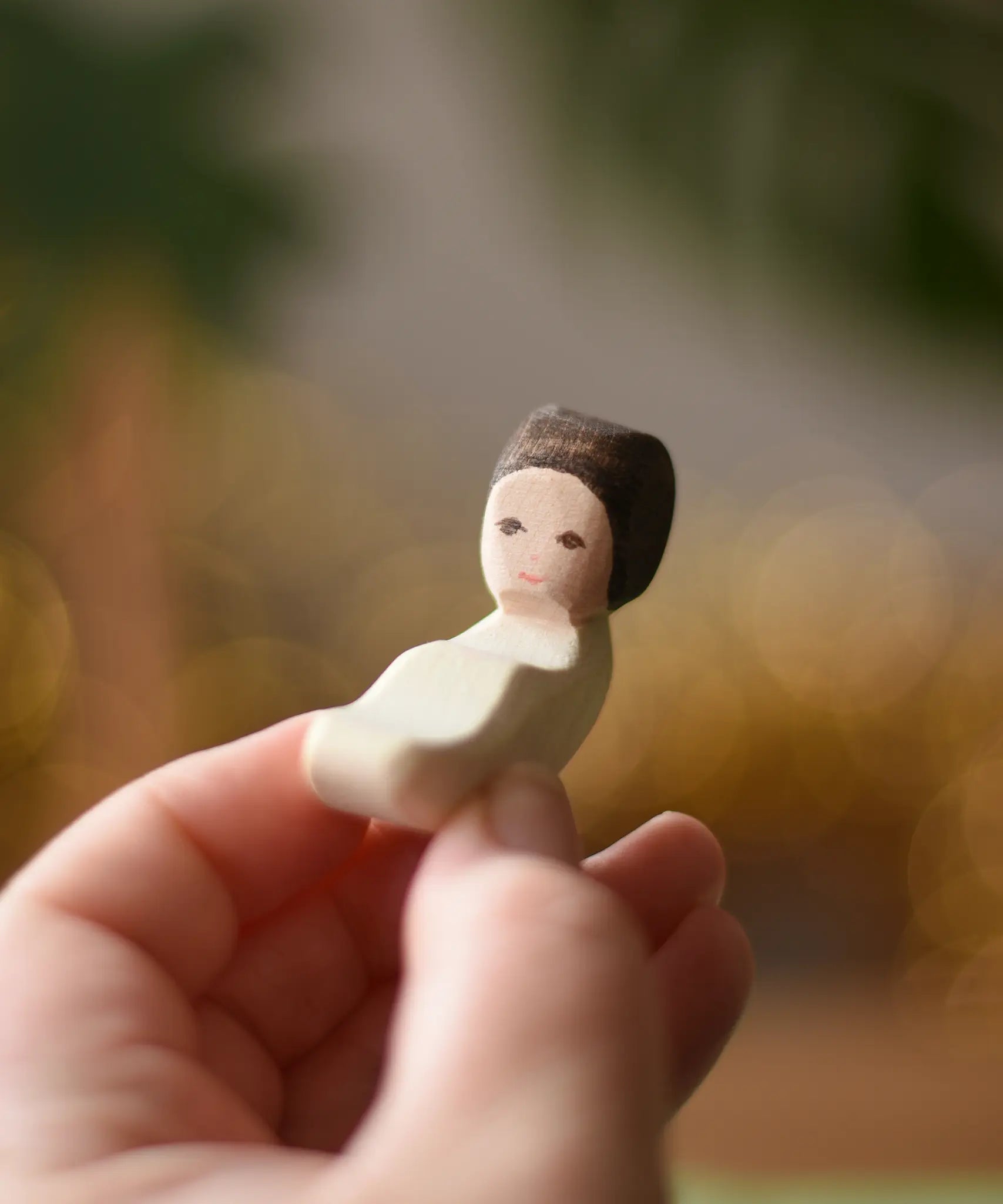 Ostherimer baby wooden toy figure in an adult's hand. 