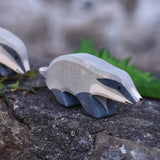 An Ostheimer wooden badger figure with straight head placed on a stone wall outdoors. Another badger figure can be seen in the background.