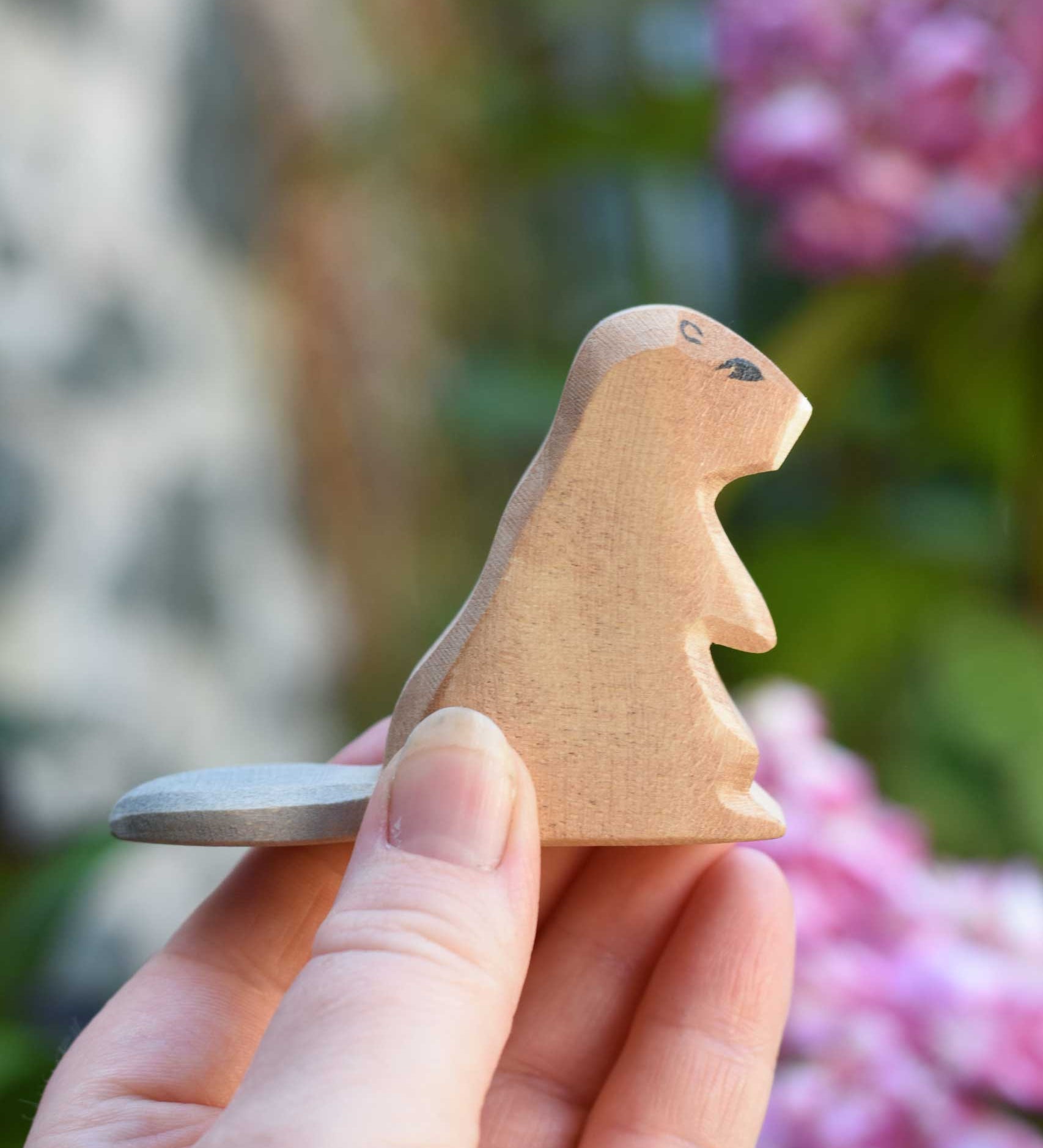 An Ostheimer sitting beaver wooden toy figure in an adult's hand to show scale. Check out our full range of expertly crafted wooden toy figures and scenery here at Babipur.