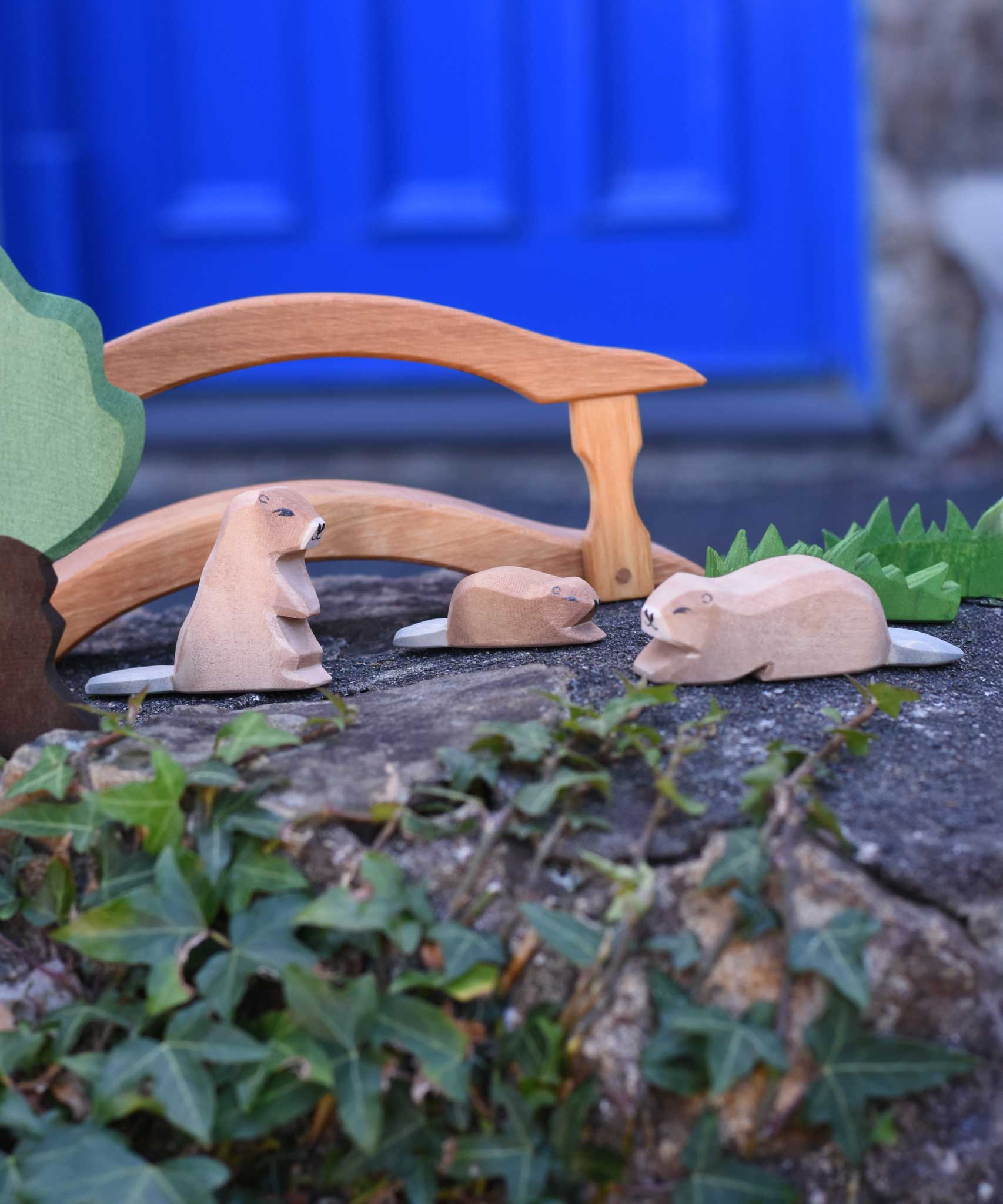 Three Ostheimer beavers shown in a small world play scene. One sitting, one laying down with a small beaver in the background. Check out our full range of expertly crafted wooden toy figures and scenery here at Babipur.