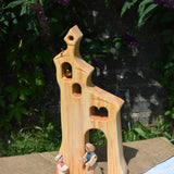 An Ostheimer wooden bell tower placed on a small table outdoors. These wooden figures are part of a large range of expertly hand crafted, Waldorf inspired, wooden toys here at Babipur.