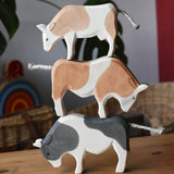 Ostheimer black and white ox, brown and white ox and a brown and white cow wooden toy figures stacked on top of each other.